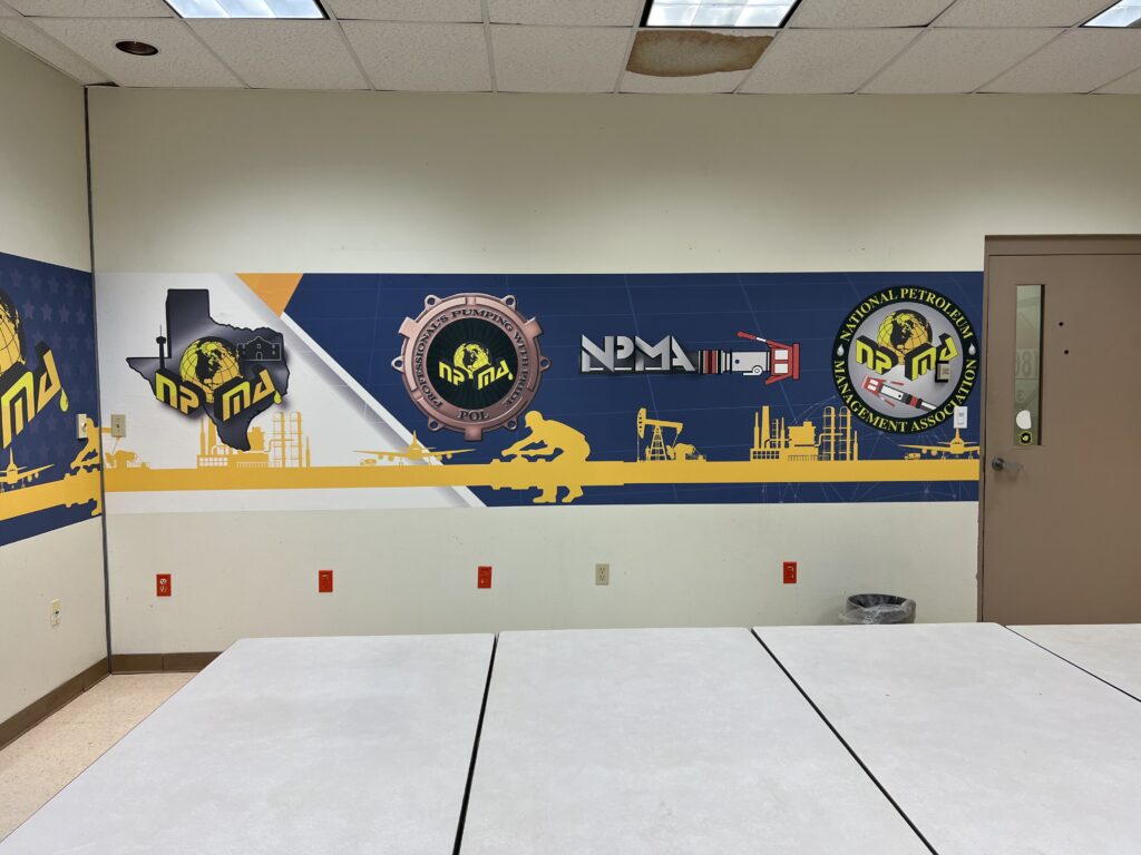 An image of a decorated wall with graphics from NPMC including the NPMC logo on an outline of the state of Texas and a refueling nozzle